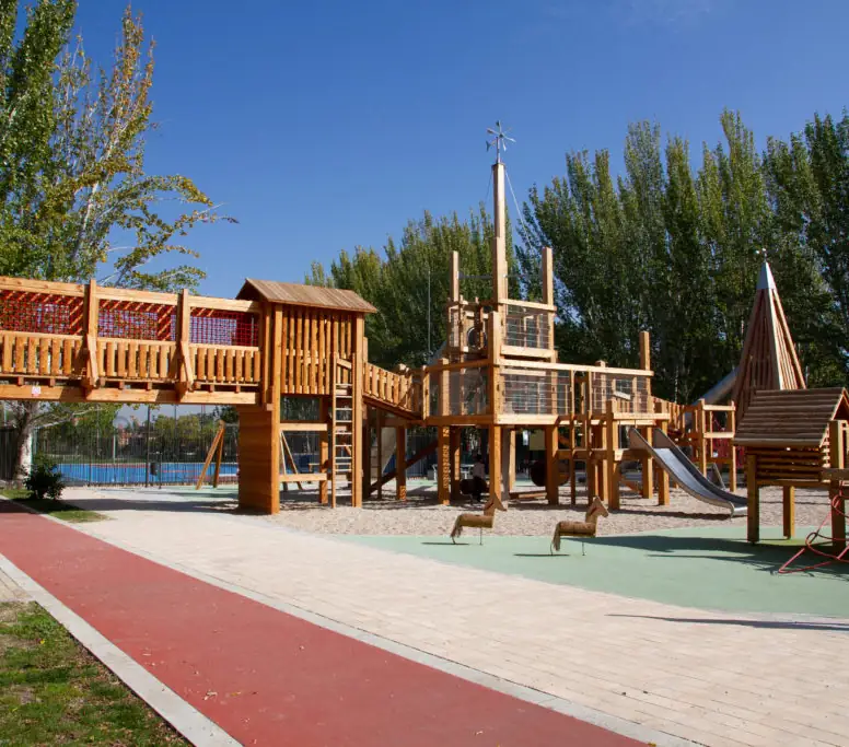 Zona de juegos infantiles de madera junto a un recorrido al aire libre